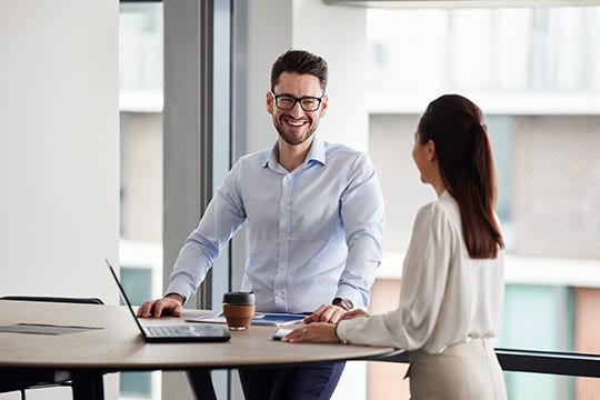 Two BlueScope employees standing in a meeting room next to a laptop