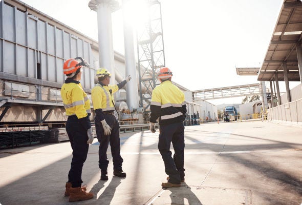 Four people in protective headware in conversation outside BlueScope facility