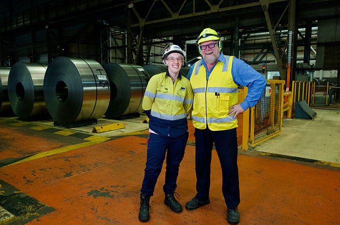 Two smiling BlueScope employees in PPE uniform in an operations setting